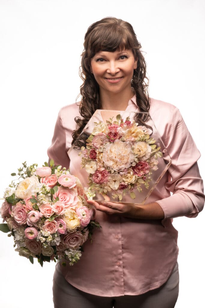florist holding fresh flowers and preserved flowers in resin