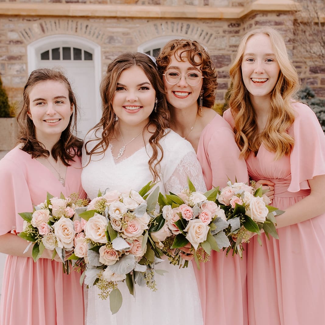 bride with her bridesmaids holding flowers