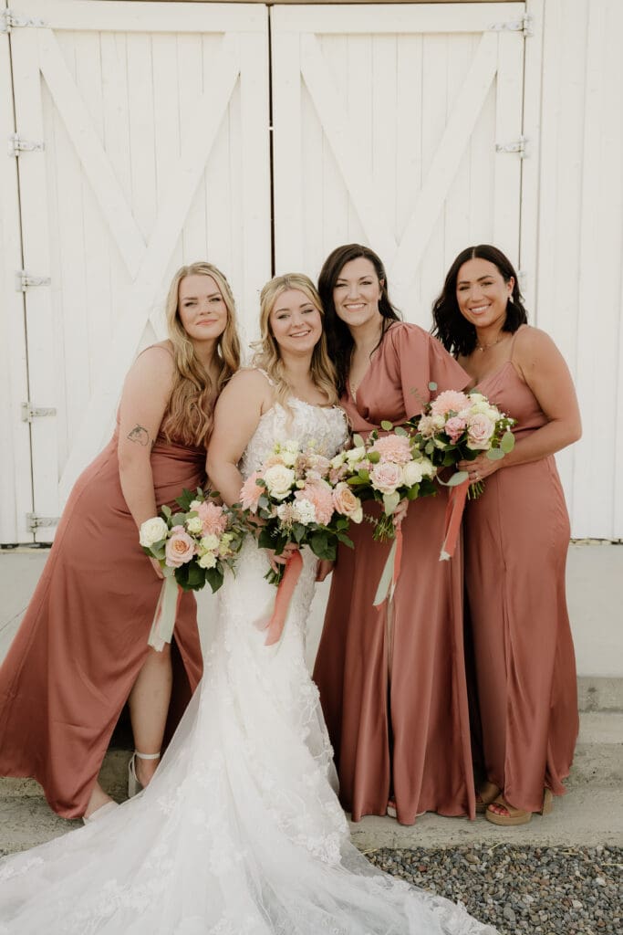 bride with her bridesmaids holding blush and white flowers